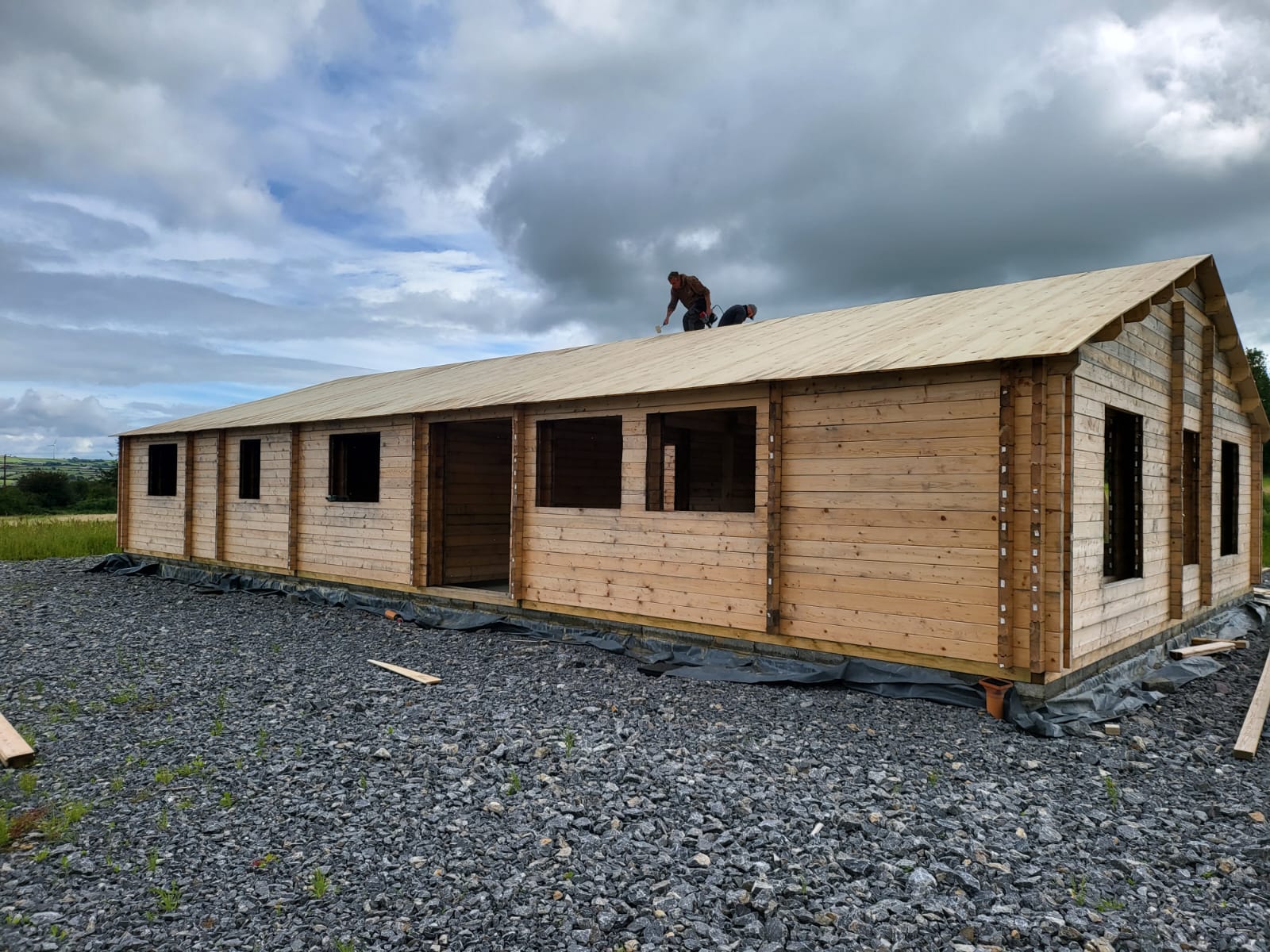 A worker on the roof of a timber frame house being constructed